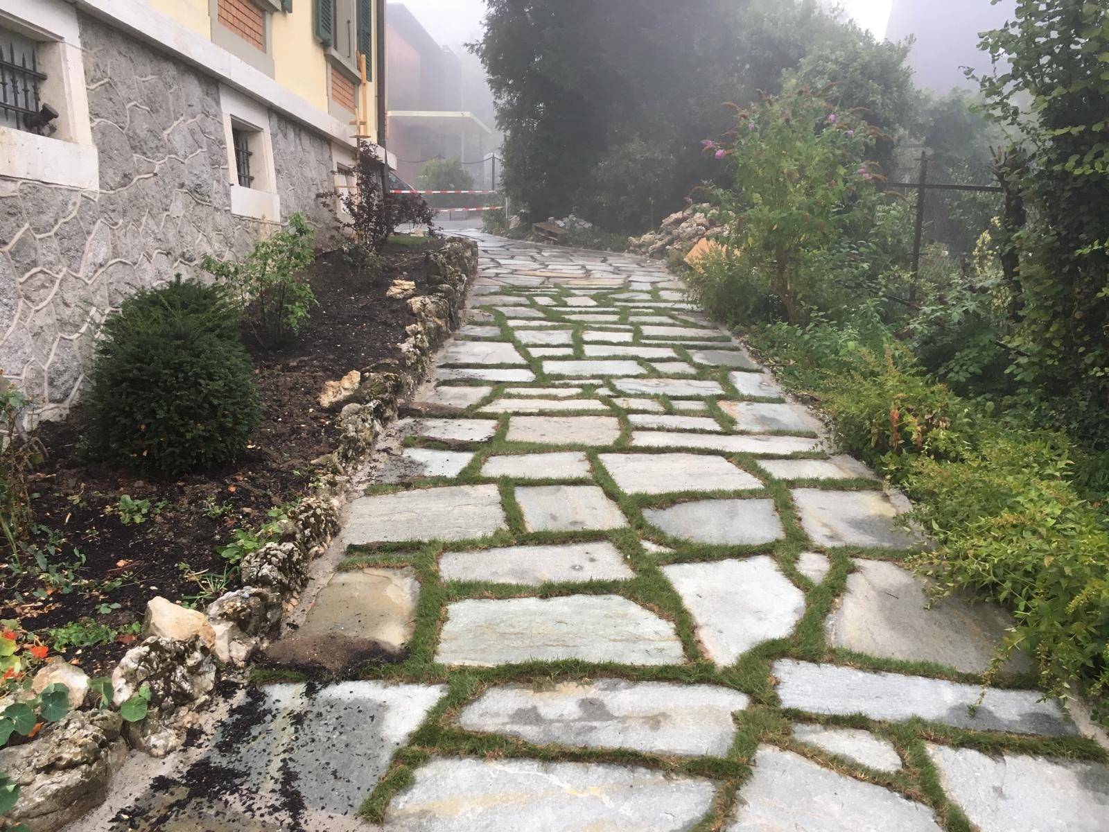 Allee de jardin en dalles de pierre naturelle avec joints engazonnes, ambiance brumeuse