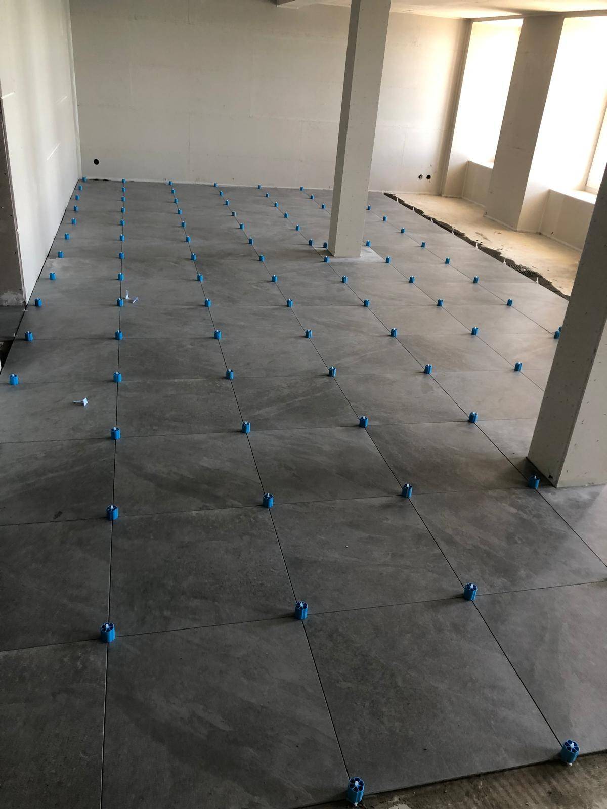 Pose de carrelage grand format gris avec croisillons de nivellement