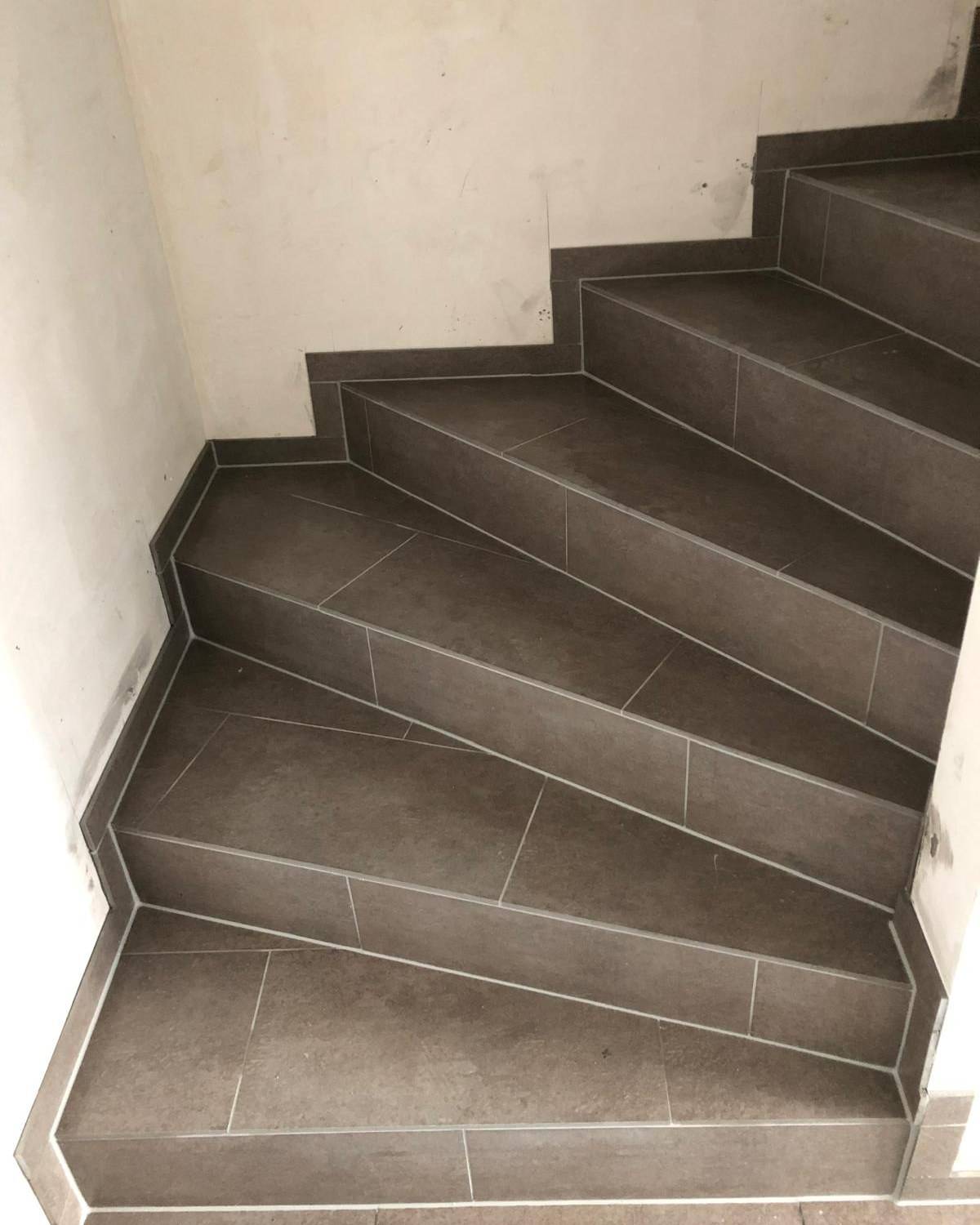 Escalier interieur en carrelage effet bois avec nez de marches noirs et main courante metallique