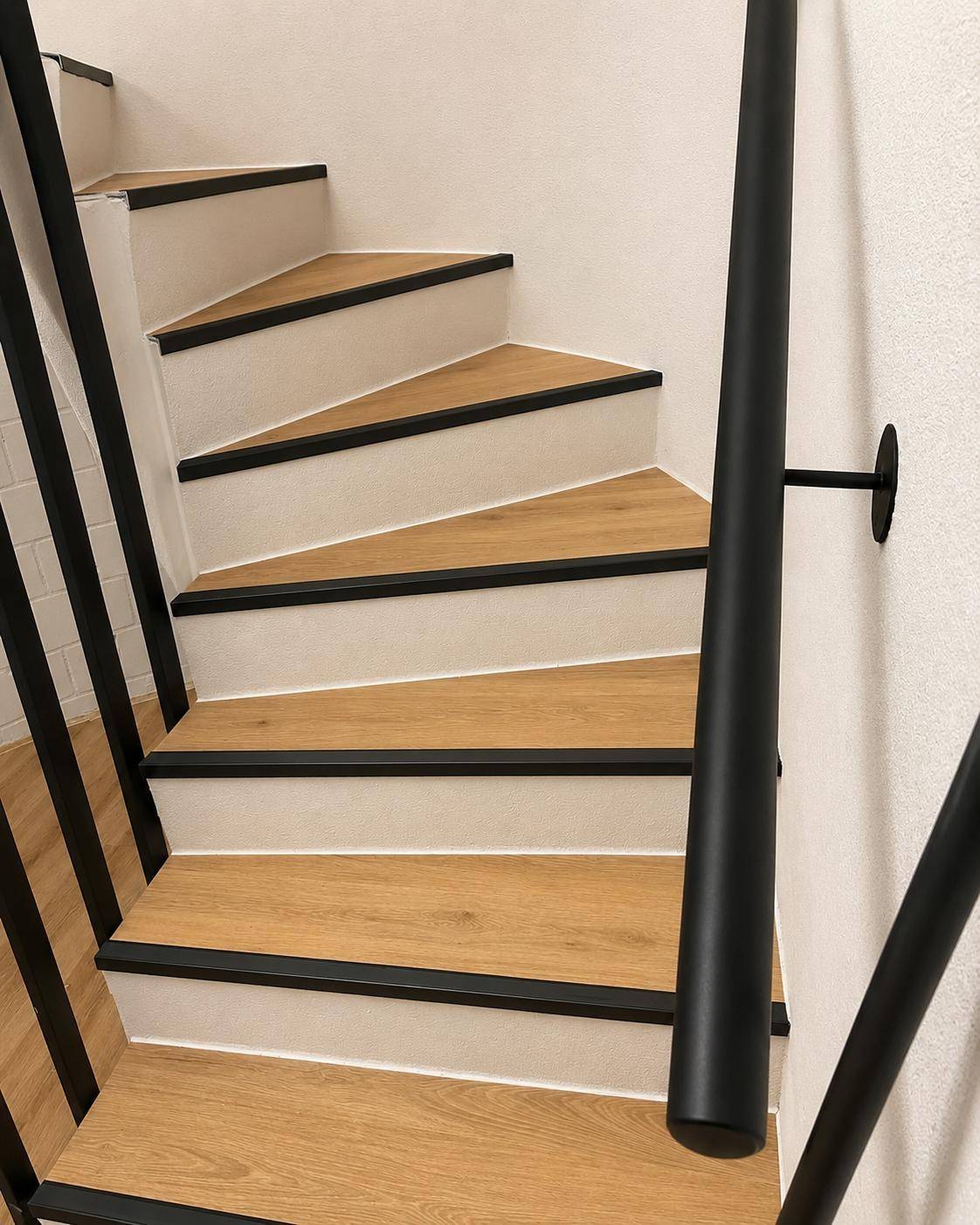 Escalier tournant habille en chene clair avec nez de marches noirs et rampe metal noir