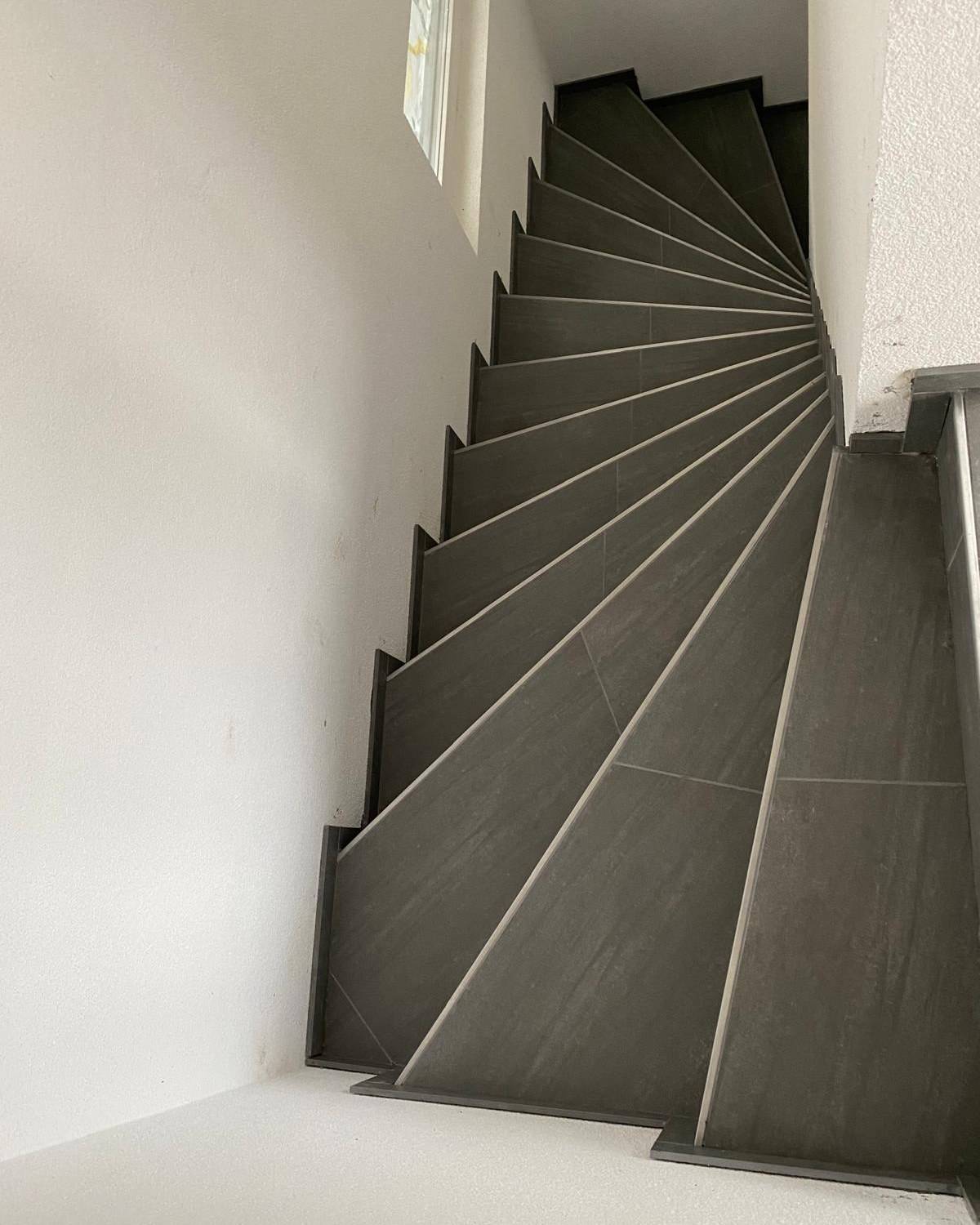 Escalier en carrelage effet bois et rampe metallique noire, vue en plongee