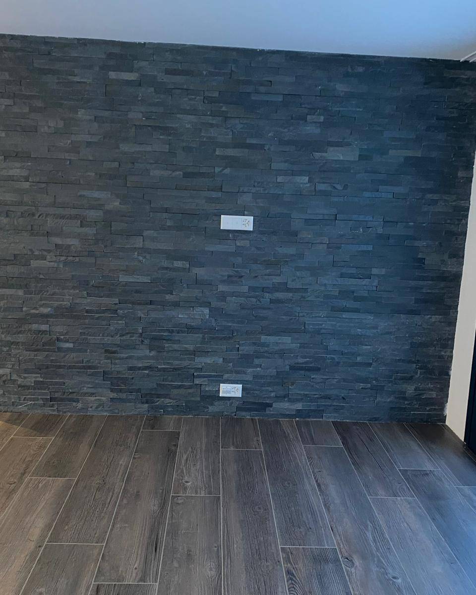Salon avec mur d'accent en pierre ardoise noire et sol effet bois