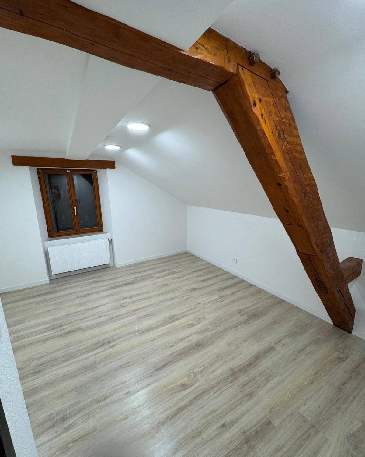 Piece mansardee renovee avec parquet chene clair et charpente apparente